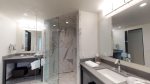 Two separate vanity granite sinks and corner marble walk-in shower
